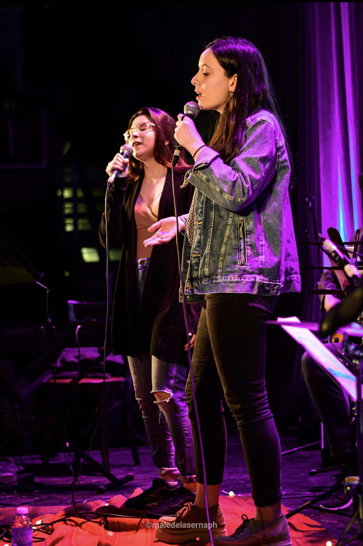Dúo de voces femeninas cantando en el escenario
