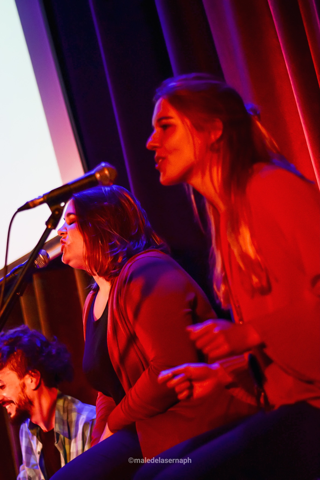 Tres alumnas cantando juntas con luces rojas
